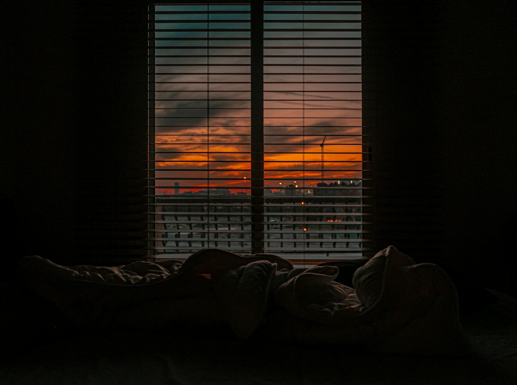 Crumpled blanket in dark room at sunset