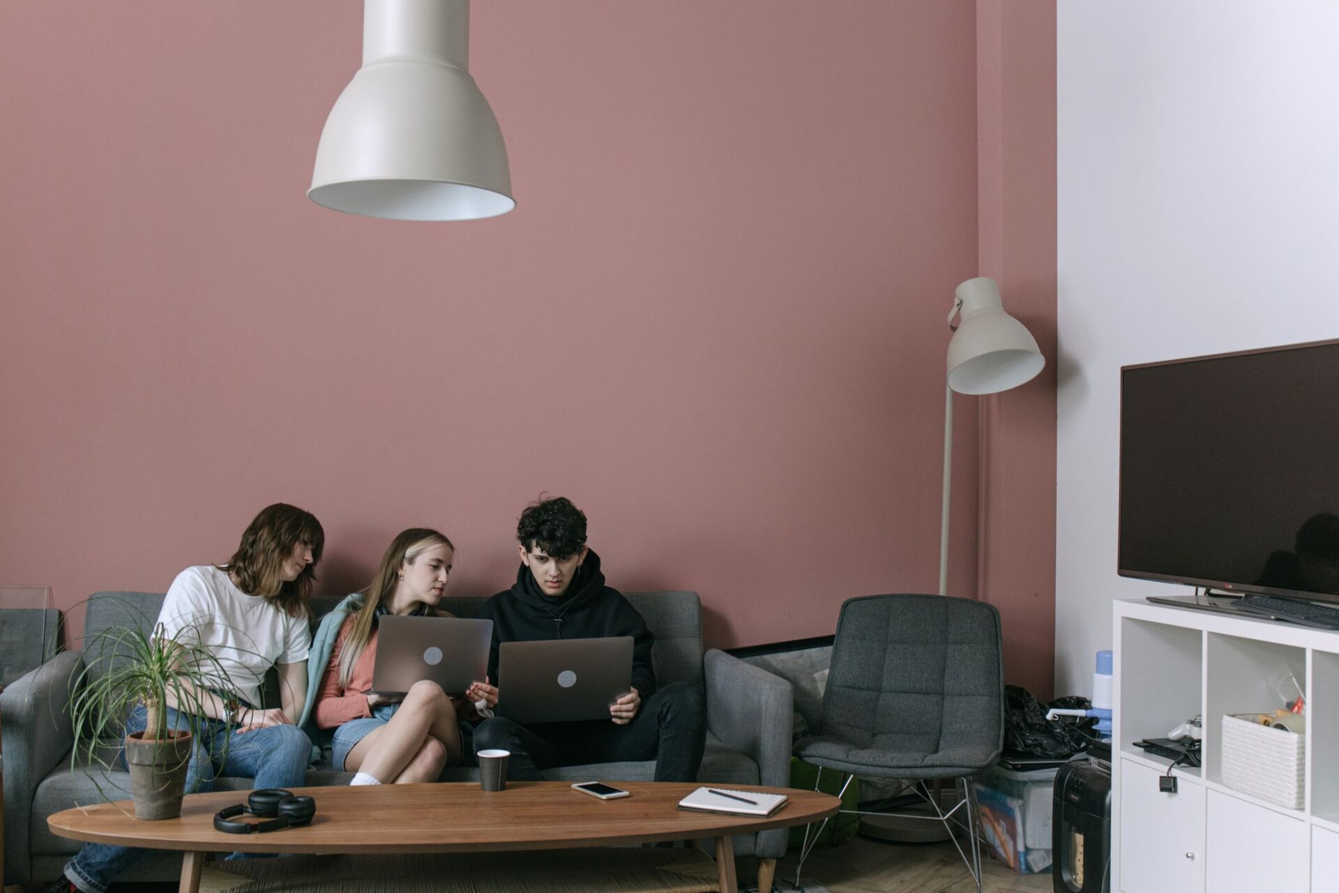 Adults discussing and working on laptops in a cozy living room setting.